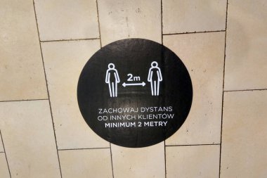 Alışveriş merkezindeki bir fayansta, koronavirüsün yayılması nedeniyle iki metrelik mesafeyi korumakla ilgili bir uyarı vardır. Sosyal uzaklık, Covid-19 'un yayılması.