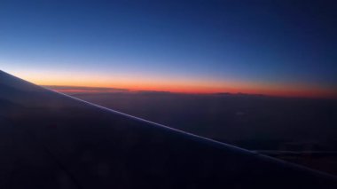 Sunset view from an airplane, featuring a vibrant horizon blending orange and blue hues. the airplane wing leads the eye to the sunset, symbolizing travel, wanderlust, and the allure of flight.