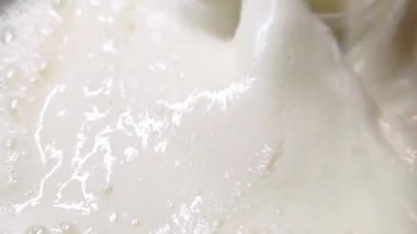 Close-up of a thick, creamy white liquid splashing, showcasing its smooth texture and rich appearance. ideal for culinary projects, dairy-related branding, or advertisements emphasizing purity and freshness.