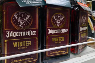 Wroclaw, Polonya, 22 Kasım 2025: Bir mağaza rafında zengin, koyu renkli ambalajlı ikonik markalar sergilenen Jagermeister kış baskısı şişeleri sergilenmektedir. Perakende ortamlarda mevsimlik promosyonlar ve şenlikli içecek seçenekleri için ideal.