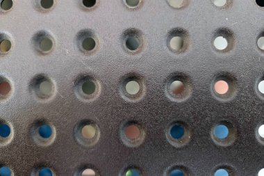 Dairesel deliklerin tek bir desenli koyu metalik yüzeyinin yakın görüntüsü. Dokulu materyal endüstriyel tasarım projeleri için idealdir, modern, minimalist estetik.