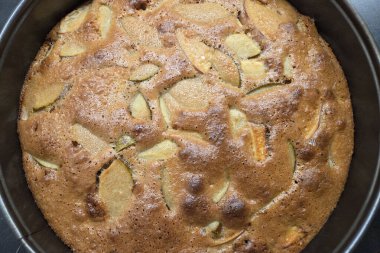 Altın sarısı ev yapımı elmalı kekin yakın plan görüntüsü, desenli kabuğu ve görünür elma dilimleri. Sonbahar kutlamaları için ideal, bu lezzetli tatlı gösterileri, kırsal ve samimi mutfak cazibesinin bir karışımı..