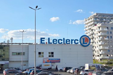 Wroclaw, Polonya, 4 Temmuz 2025: E.leclerc süpermarketlerin ön yüzü modern apartman binalarının arka planına belirgin bir şekilde karşıdır. Arabalar ön tarafa park edilmiş, açık mavi gökyüzünün altında etkin bir alışveriş atmosferi yaratıyorlar.