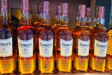 Wroclaw, Polonya, 5 Ağustos 2025: Dewar 'ın 12 yıllık viski şişeleri bir mağaza rafına düzgünce dizilmiş. Zengin kehribar renkleri ve zarif etiketlerle, yaşlanmış ruhların cazibesini vurguluyorlar, uzmanlara ve koleksiyonculara hitap ediyorlar..