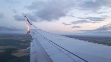 Wroclaw, Polonya, 27 Haziran 2025: Ticari bir uçuşta pencere kenarından sakin bir manzara, rengarenk gökyüzünün arka planına karşı uçak kanatlarını gösteriyor. Ufuk geniş manzaralara sahip, sakin ve resimsel bir ortam yaratıyor.