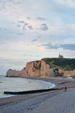 Etretat 'ın manzaralı kıyı şeridi dramatik kireçtaşı uçurumları ve sakin bir plaja sahiptir. Uçurumun tepesinde, doğa ve mimarinin ahenkli karışımını sembolize eden büyüleyici bir kilise oturuyor. Ziyaretçiler sakin sahil atmosferinin tadını çıkarıyorlar..