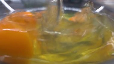 Ham yumurta içeriği cam bir kâse içinde canlı renkler ve dokular sergiliyor. Taze yumurta sarısı, şeffaf beyazla çelişiyor. Görsel olarak hoş bir hareket ve durgunluk karışımı oluşturuyor..