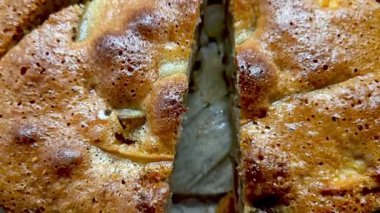 Yeni pişmiş elmalı turtanın yakın plan görüntüsü, altın, sarkık kabuğunu ve büyüleyici dokusunu gözler önüne seriyor. Keskin bir bıçak, sonbahar toplantıları ve şenlikli durumlar için ideal bir kesit için yerleştirilmiştir..