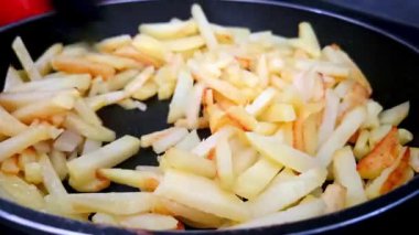 Kızarmış patatesler siyah bir tavada cızırdıyor, çıtır çıtır bir dokuda ve davetkar bir sıcaklıkta. Yemek blogları, aşçılık makaleleri ya da fast food promosyon malzemesi için ideal, klasik konforlu yemek hazırlama.