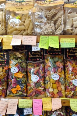 Floransa, İtalya, 31 Aralık 2025: Renkli ambalajlar içeren İtalyan makarna seçimi çeşitli şekil ve boyutlarda raflarda sergilenmektedir. Penne, fusilli, ve spagetti çeşitleri, el yazısı notlar ve canlı renkler ile süslenmiş