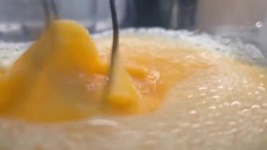 Yumurtaların çırpılmasına, dinamik hareketlere ve köpüklü dokulara yakın çekim. Mutfak temalı tasarımlar için ideal, bu canlı görüntü ev yapımı kahvaltı hazırlıklarının özünü somutlaştırıyor.