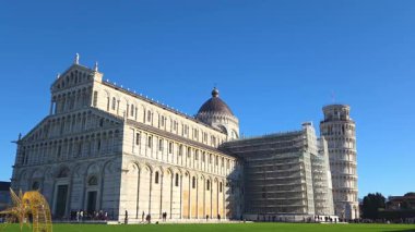 Pisa, İtalya, 27 Aralık 2025: Pisa katedrali ve simgesel eğimli kule, parlak mavi gökyüzüne karşı, İtalya 'nın pisa şehrinde görkemli bir şekilde durmaktadır. Sahne tarihsel ve mimari önemi birleştiriyor, canlı yeşil çimlerle zenginleştiriliyor, sergileniyor