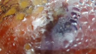 Rengarenk buz dokularına yakından bakan canlı ve soyut bir görüntü. Kompozisyon, mor, turuncu ve beyaz kıvrımlı şekiller sergiliyor, kabarcıklar ve don dinamik ve çekici bir görsel etki yaratıyor..