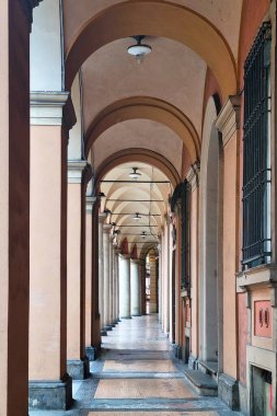 Bologna, İtalya, 4 Ocak 2026: Çarpıcı bir mimari koridorda klasik Avrupa tasarım unsurları, zarif kemerler, süslü sütunlar ve klasik ışıklandırma yer alıyor. Perspektif görünümü tarihin simetrisini ve zamansız güzelliğini vurgular