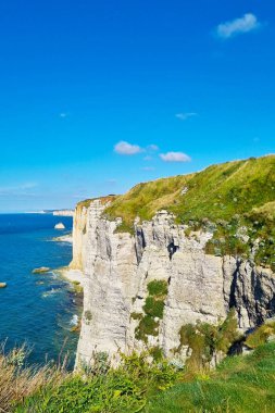 Dalgalı mavi bir okyanusa karşı yükselen uçurumların nefes kesici manzarası. Uçurumların tepesindeki gür yeşillik engebeli kaya oluşumlarıyla çelişiyor. Birkaç bulut berrak bir mavi gökyüzüne doğru süzülür ve dingin atmosferi güçlendirir..