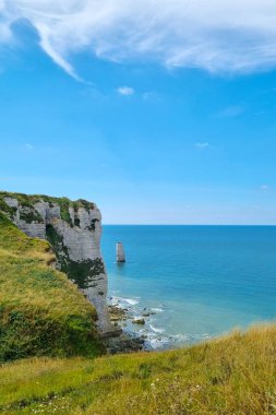 Resmedilmeye değer sahil kayalıkları açık mavi denizle canlı bir gökyüzünün altında buluşuyor. Kaya oluşumları sakin okyanusa doğru uzanırken yemyeşil çimenler kayalıkları kaplar. Doğa, seyahat ve peyzaj tasarım temaları için mükemmel.