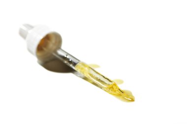 Beyaz arka planda izole edilmiş pipetteki sıvı yağ serumu damlası. Retinol, aha, bha asit, kolajen cilt sıvısı, yüzeysel alan derinliğinde fotoğraf. Güzellik tedavisi için altın özü.