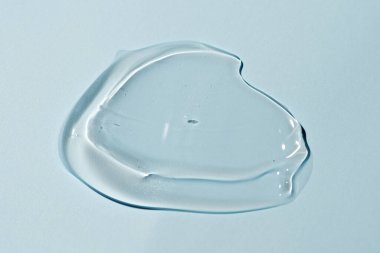 Mavi arkaplanda sıvı jel izi var. Saf şeffaf aloe losyonu, yüz jölesi serumu, temizleyici, duş jeli ya da şampuan gibi kozmetik lekeler.