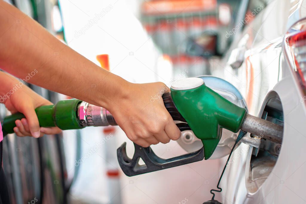 Filling up the car with petrol. Womans hands pouring gasoline or gas into her car tank at fuel station