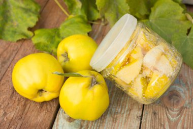 Ayva, ahşap arka planda bıldırcın şekerli cam kavanoz..