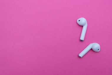 Pembe arka planda kablosuz beyaz kulaklık. Boşluğu kopyala