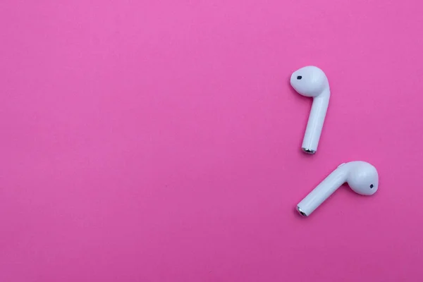 Pembe arka planda kablosuz beyaz kulaklık. Boşluğu kopyala