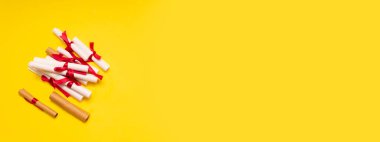 Sarı arka planda kırmızı şeritli beyaz ve kahverengi kağıtlar..