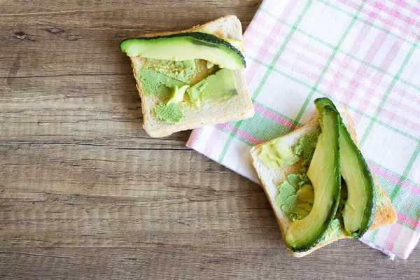 Ahşap bir masada avokadolu tostlar, yukarıdan manzara. Sağlıklı yeme kavramı