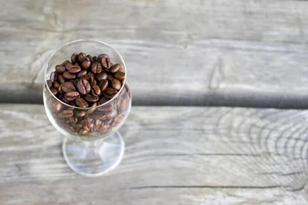 Kahve taneleri, tahta zemin üzerinde kahve taneleri olan cam kadehler.