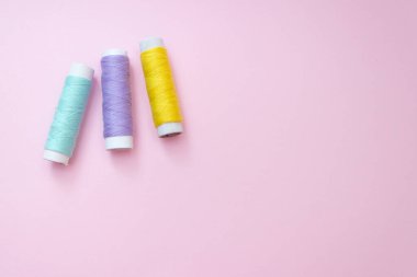 Pembe arkaplanda renkli dikiş ipliği