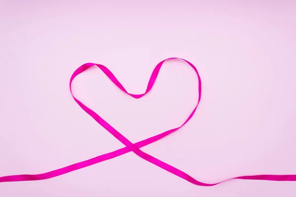 Yumuşak bir zeminde pembe kurdelelerden yapılmış bir kalp.