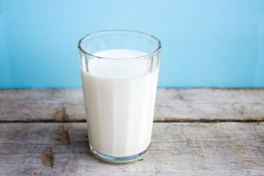 Tahta bir masanın üzerindeki bardakta süt. Taze süt