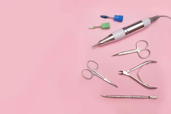 Çivi aleti. Profesyonel çelik manikür ve pedikür aletleri. Manikür makası, maşa, maşa, makas, makas ve pembe arka planda oje sürmek için başlık..
