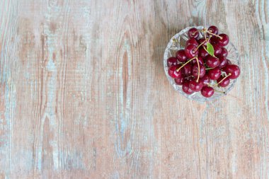 Olgun kirazlar, kirazlar ahşap bir arka planda fotokopi alanı olan bir tabakta. Çilekli.