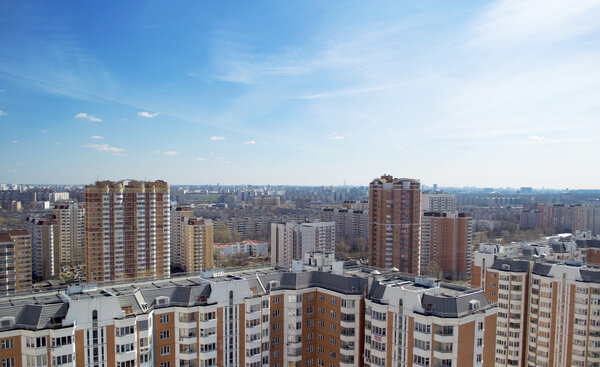 The view from the window of a tall building on a cityscape. Sunny weather and blue sky. Dense buildings