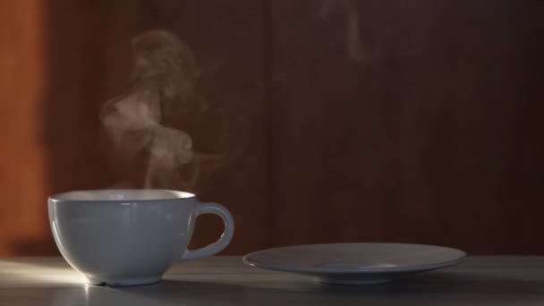 Vrouwelijke handen gieten hete zwarte thee in een wit kopje en een taart op een wit bord. Stoom uit de beker. — Stockvideo