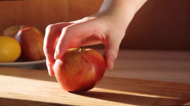 Ahşap bir masada elma kesen bir kadın.