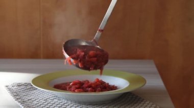 Rus çorbası döken kadın elleri tabağa konuyor.