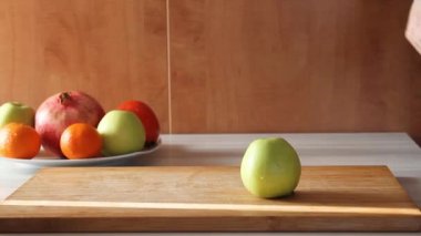 Bıçakla kesen kadın elleri mutfaktaki ahşap masada duran bir elma.