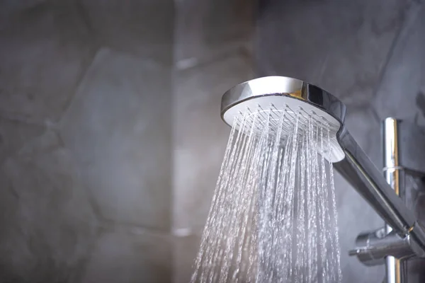 Closeup of shower head with running water in the bathroom. Cold water therapy.