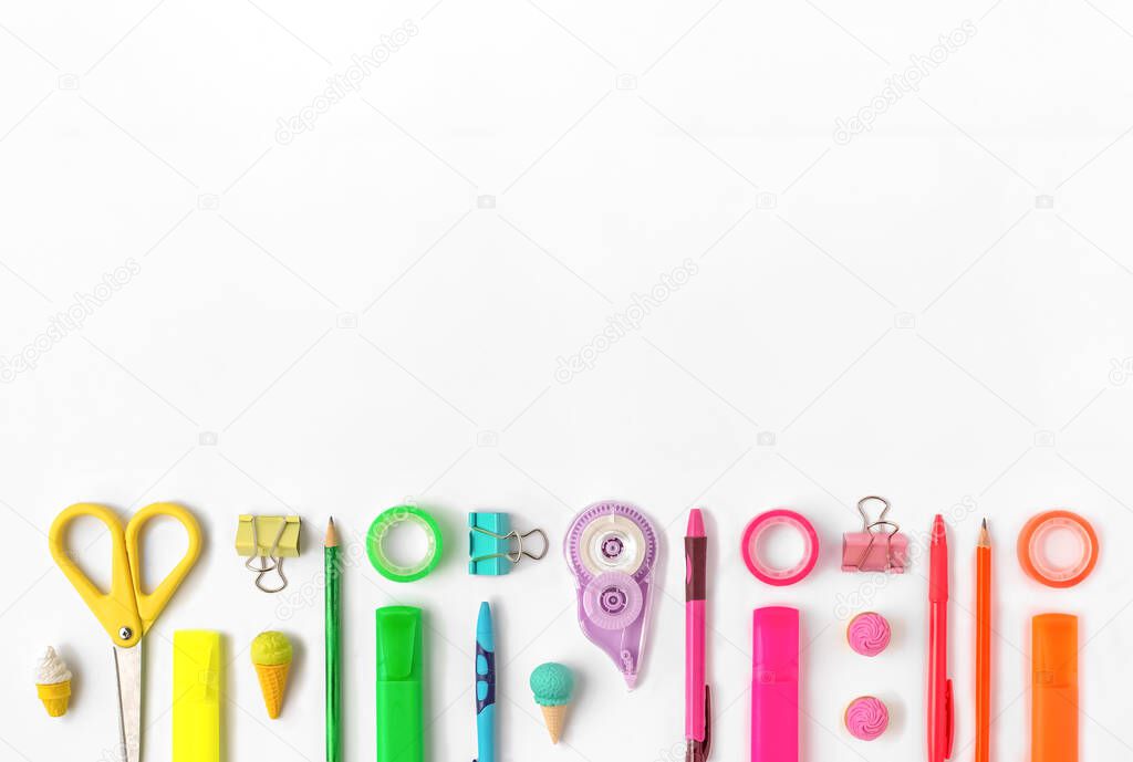 School stationary supplies in rainbow colors decorating white background with copy space. Back to school concept. Top view.