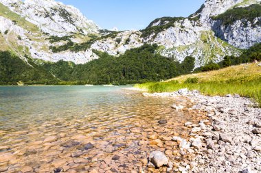 Turquoise high mountain lake with crystal pure waters surrounded by rocky mountains in Montenegro. Trnovacko lake near Maglic mountain. 
