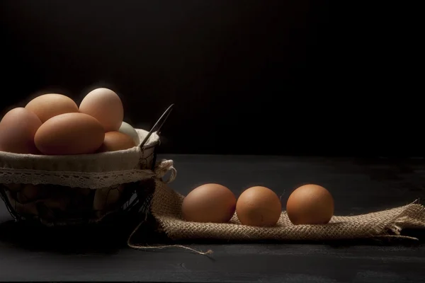 Καλάθι σύρμα με φρέσκα αυγά σε σκούρο φόντο Εικόνα Αρχείου