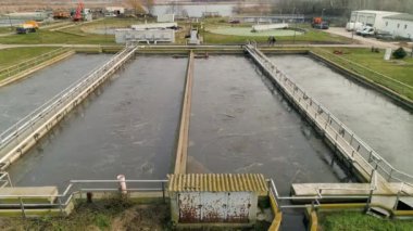 Lağım atığı su ayırma tankları. Uzaklara uç. Lağım ayrıştırma tankları dairesel ve dikdörtgen. Yakındaki göl.