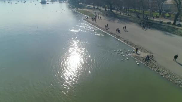 Tuna Nehri kıyısı. Kuğular ve insanlar güzel bir günün tadını çıkarıyorlar. Güneş yansıması. İHA atışı. — Stok video