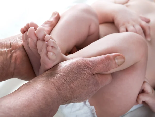 Mormor stickade baby strumpor varm, ta hand om barnet — Stockfoto