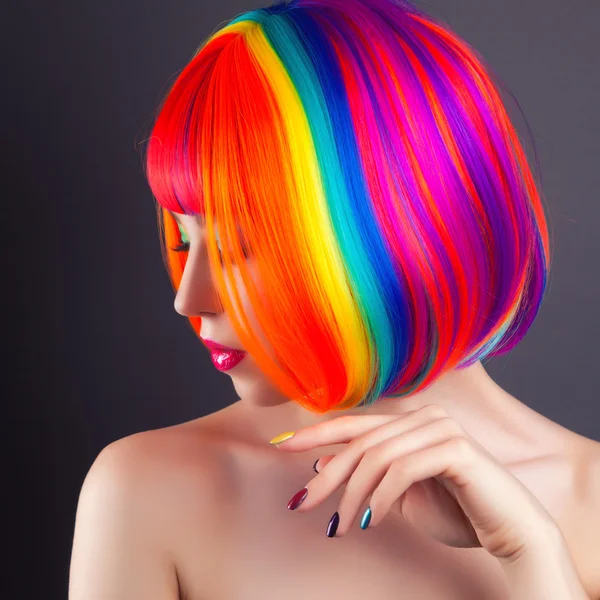 Bela mulher vestindo peruca colorida e mostrando unhas coloridas — Fotografia de Stock