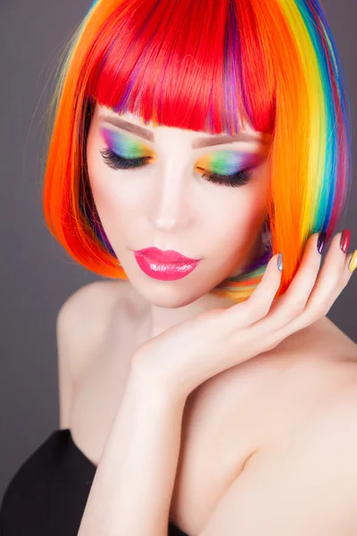 Hermosa mujer vistiendo peluca colorida y mostrando uñas coloridas —  Fotos de Stock