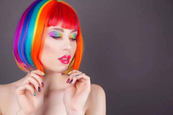 Hermosa mujer vistiendo peluca colorida y mostrando uñas coloridas — Foto de Stock