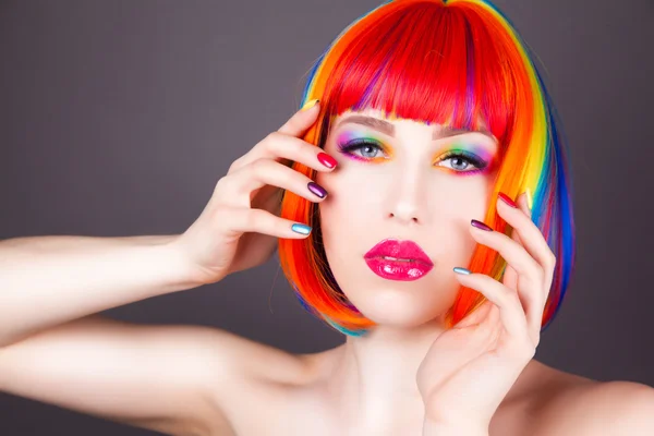 Hermosa mujer vistiendo peluca colorida y mostrando uñas coloridas —  Fotos de Stock